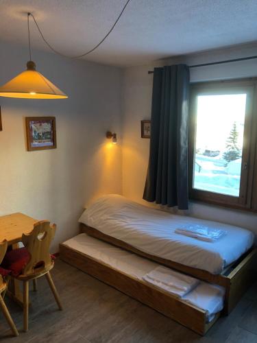 a bedroom with a bed and a window and a table at Cembros 2 in Méribel
