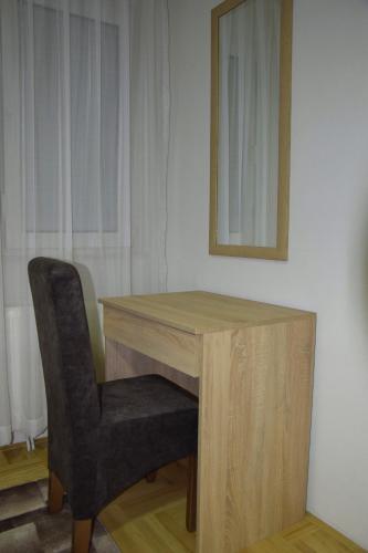 a wooden desk with a chair and a mirror at Apartmani Marić in Novi Pazar