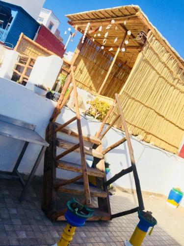 a wooden ladder next to a building with a roof at tamazirt surf house in Taghazout