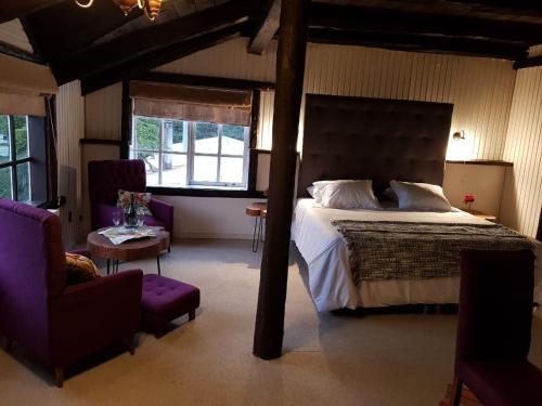 a bedroom with a large bed and two chairs at The Patagonian Lodge in Coihaique