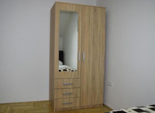 a wooden cabinet with a mirror in a room at Apartmani Marić in Novi Pazar