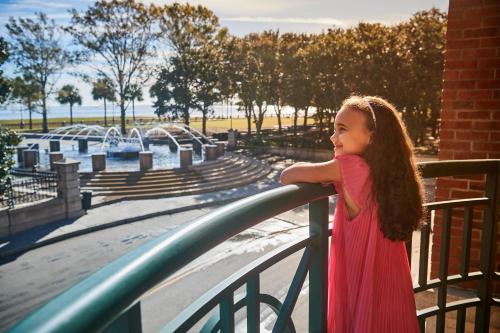a little girl in a red dress leaning on a railing at Harbourview Inn in Charleston