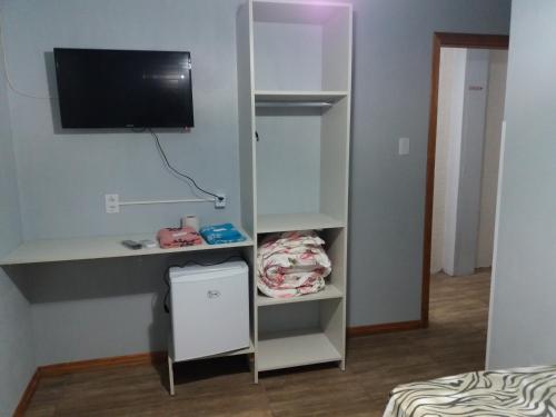 a room with a tv and a shelf with a bed at Hotel Majestic in Pelotas