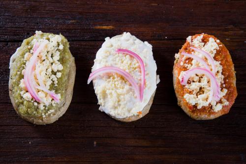 three sandwiches with white icing and pink onions on them at Hotel San Jorge in Tlatlauquitepec