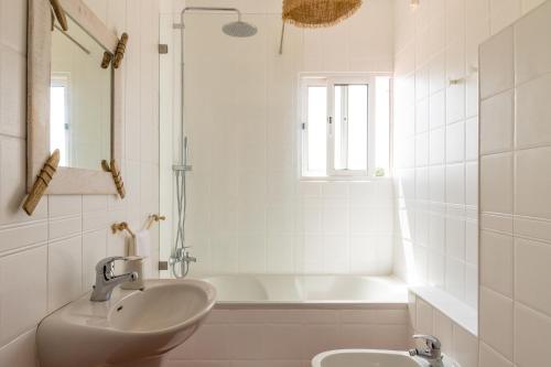 a white bathroom with a sink and a tub at Utopia in Aljezur