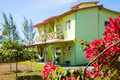 uma casa verde com uma varanda e flores cor-de-rosa em Pousada Villa Verde em Estância