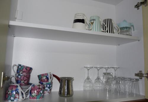 a shelf filled with wine glasses on top of a counter at Apartmani Marić in Novi Pazar