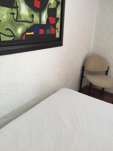 a bedroom with a bed and a chair and a painting at Hotel Casona Las Juanas in San José de Pare