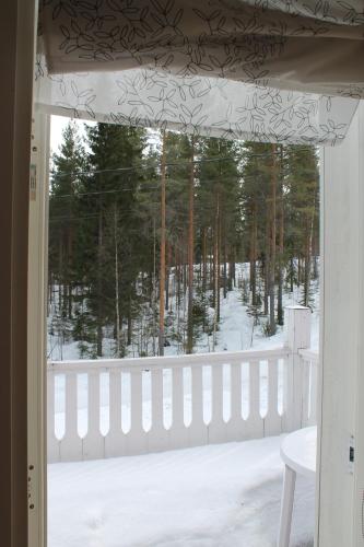 a window view of a snowy yard with a fence at Коттедж в Финляндии, Enonkoski (розовый) in Enonkoski