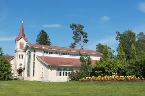 a large white church with a steeple and flowers at Коттедж в Финляндии, Enonkoski (розовый) in Enonkoski