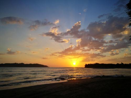 a sunset on the beach with the sun setting at Eco-Lodge Deseo Bamboo in Santa Catalina