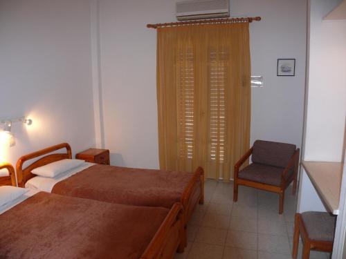 a hotel room with two beds and a chair at Sylvia Studios in Agia Marina Aegina