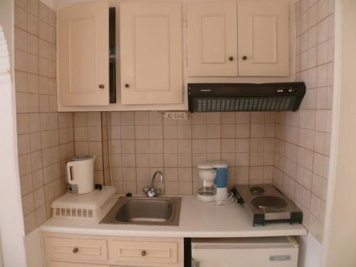 a small kitchen with white cabinets and a sink at Sylvia Studios in Agia Marina Aegina