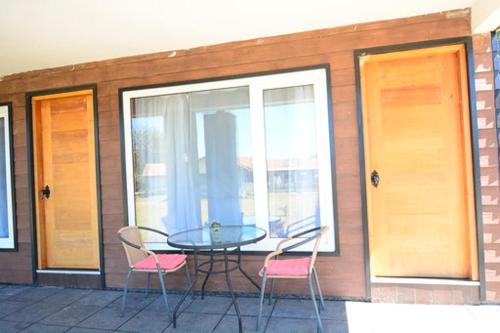 a glass table and two pink chairs on a patio at Complejo Molco Sur con Piscina in Pucón