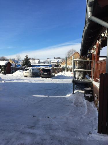 a parking lot covered in snow with cars parked at Penzion Na Solné stezce in Kašperské Hory