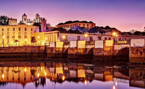 a city skyline with a bridge over water at night at Country guest house with pool in Tavira
