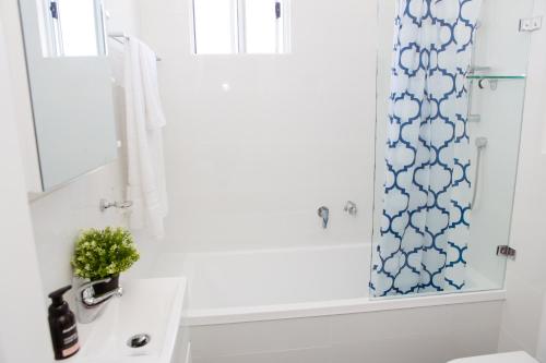 a bathroom with a sink and a shower curtain at Little Cottage Cessnock Hunter Valley in Cessnock