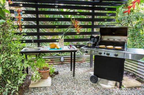 a barbecue in a garden with a table and a grill at Tico Tico Villas - Adult Only in Manuel Antonio