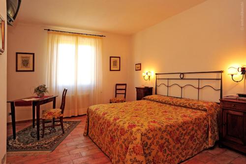 a bedroom with a bed and a table and a window at Hotel La Fonte Del Cerro in Saturnia