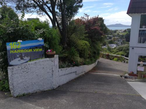 a sign on a wall next to a sidewalk at Harbour View Guesthouse in Auckland