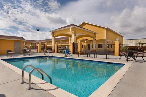 a pool at a hotel with tables and chairs at Days Inn by Wyndham Odessa in Odessa