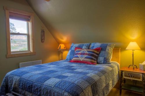 a bedroom with a bed with a blue comforter and a window at Beautiful 1 BR "Barn" Cabin - Perfect for Small Families in Panguitch