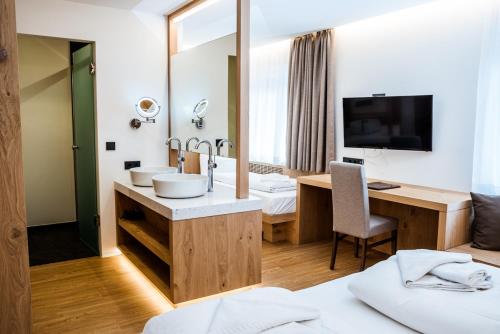 a hotel room with a bathroom with a sink and a desk at Hotel Des Alpes in Selva di Val Gardena