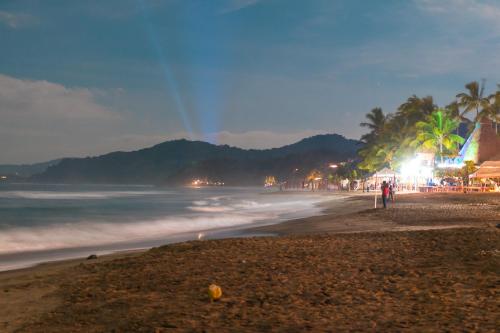 a beach at night with palm trees and the ocean at Mi Otra Casa in Sayulita