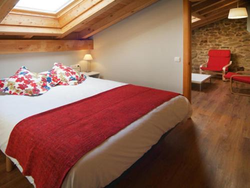 a bedroom with a large bed and a red chair at Apartamentos Lusarbe in Orio