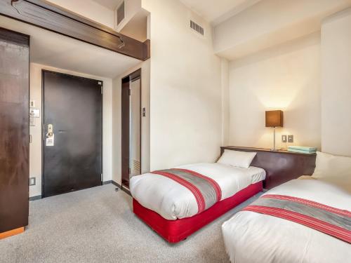 a bedroom with two beds and a door to a room at Hakuba Gondola Hotel in Hakuba