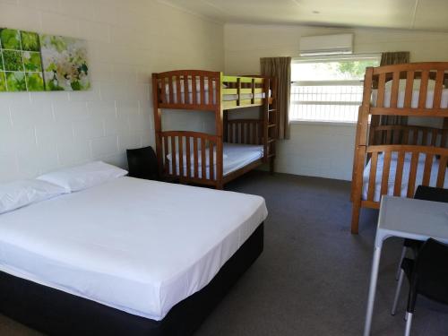 a bedroom with a bed and two bunk beds at Mawley Holiday Park in Masterton
