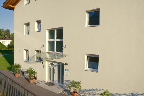 Un edificio blanco con plantas en macetas delante. en Apartment hauskaernten, en Velden am Wörthersee