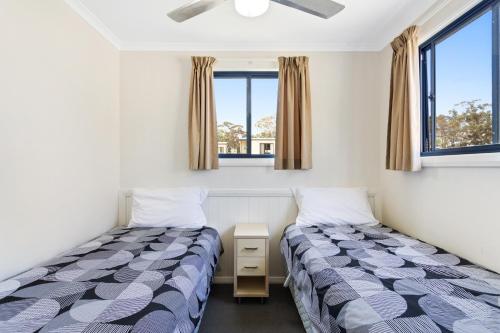 twee bedden in een kamer met twee ramen bij Goulburn South Caravan Park in Goulburn