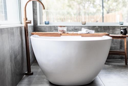 a white bath tub in a bathroom with a sink at The Woods Pokolbin in Pokolbin