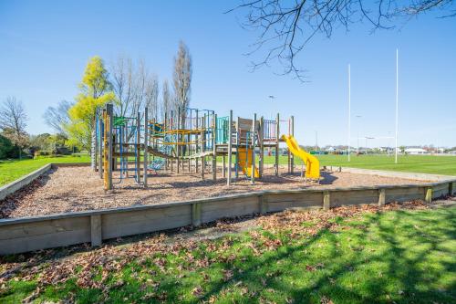 a playground with a yellow slide in a park at Christchurch Park Motel in Christchurch
