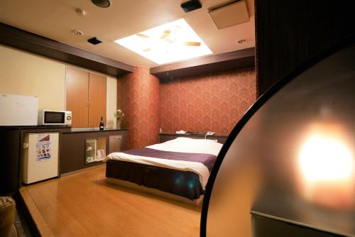 a small bedroom with a bed and a kitchen at Hotel ACQUA MYU in Fukuoka