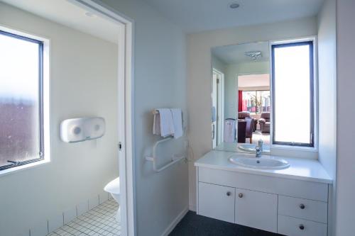 a white bathroom with a sink and a mirror at Christchurch Park Motel in Christchurch