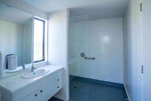 
a bathroom with a sink, mirror, and shower at Christchurch Park Motel in Christchurch
