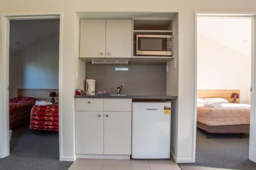 
a kitchen with a stove, microwave and refrigerator at Christchurch Park Motel in Christchurch
