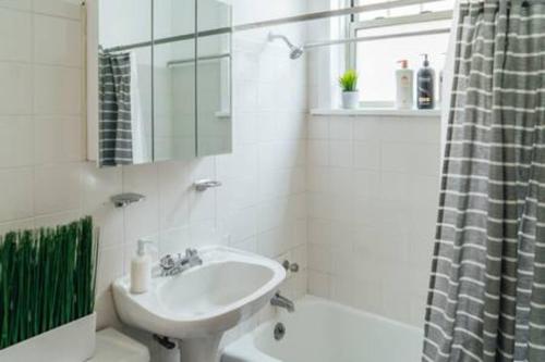 a white bathroom with a sink and a shower at Calm & Well-Equipped 2BR Chicago Apartment - Central Cozy in Dunning