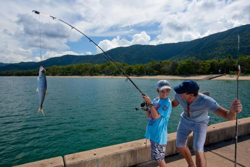 two children are fishing on a dock with a fish at Sarayi Boutique Hotel in Palm Cove