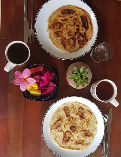 a table with two plates of food and two cups of coffee at Little Elephant Cottage in Gili Trawangan