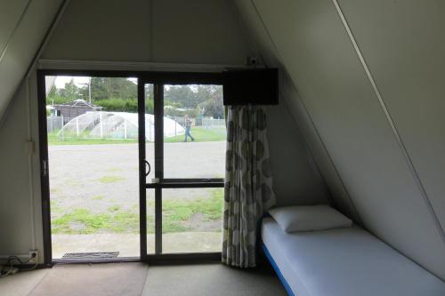 a small room with a bed and a window at Rangiora Eco Holiday Park in Fernside