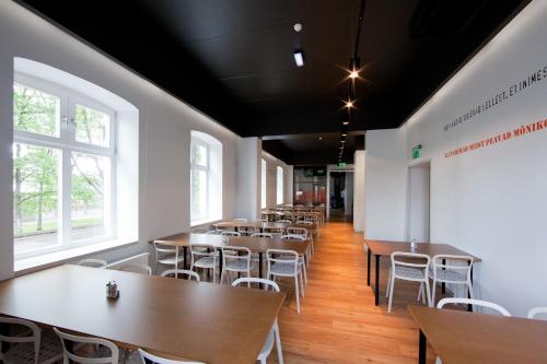 a dining room with tables and chairs and windows at Just Rest Automatic Hostel in Viljandi