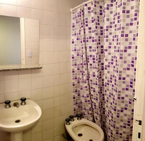 a bathroom with a sink and a toilet and a shower curtain at Hotel Positano in Mar del Plata