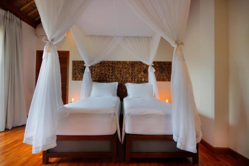 two beds in a bedroom with a canopy bed at Villa Arcadia in Gianyar