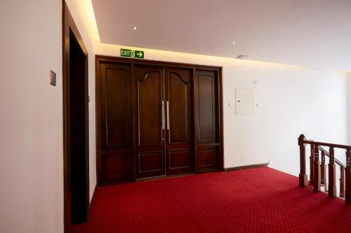 a room with two wooden doors and a red carpet at Galway Heights Hotel in Nuwara Eliya