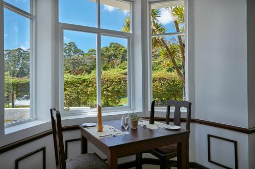 a table and chairs in a room with windows at Galway Heights Hotel in Nuwara Eliya