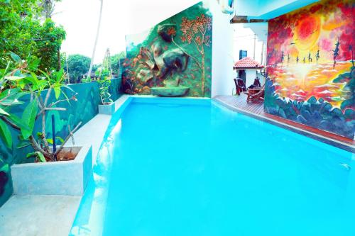 a swimming pool with a painting on the wall at Hotel Sanmark in Ahangama