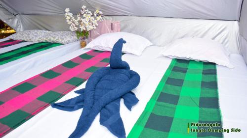 a bed with a blue stuffed dolphin on it at Sigiri Jungle Camping in Sigiriya